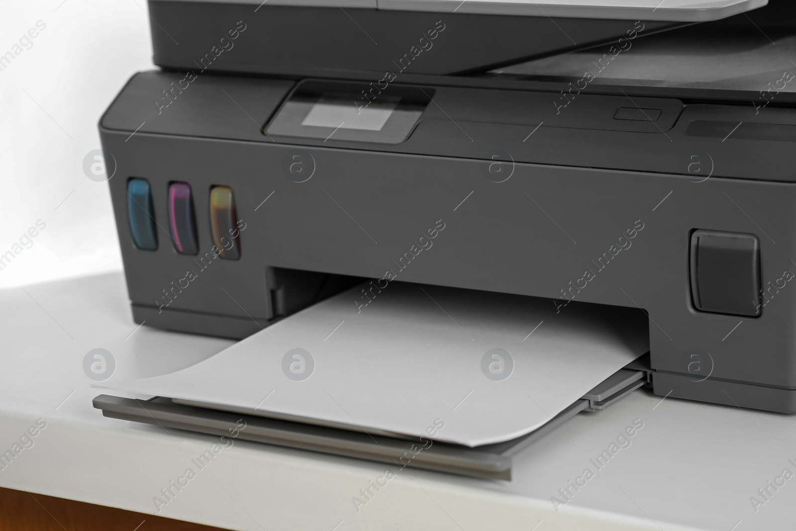 Photo of Modern printer with paper on white table, closeup