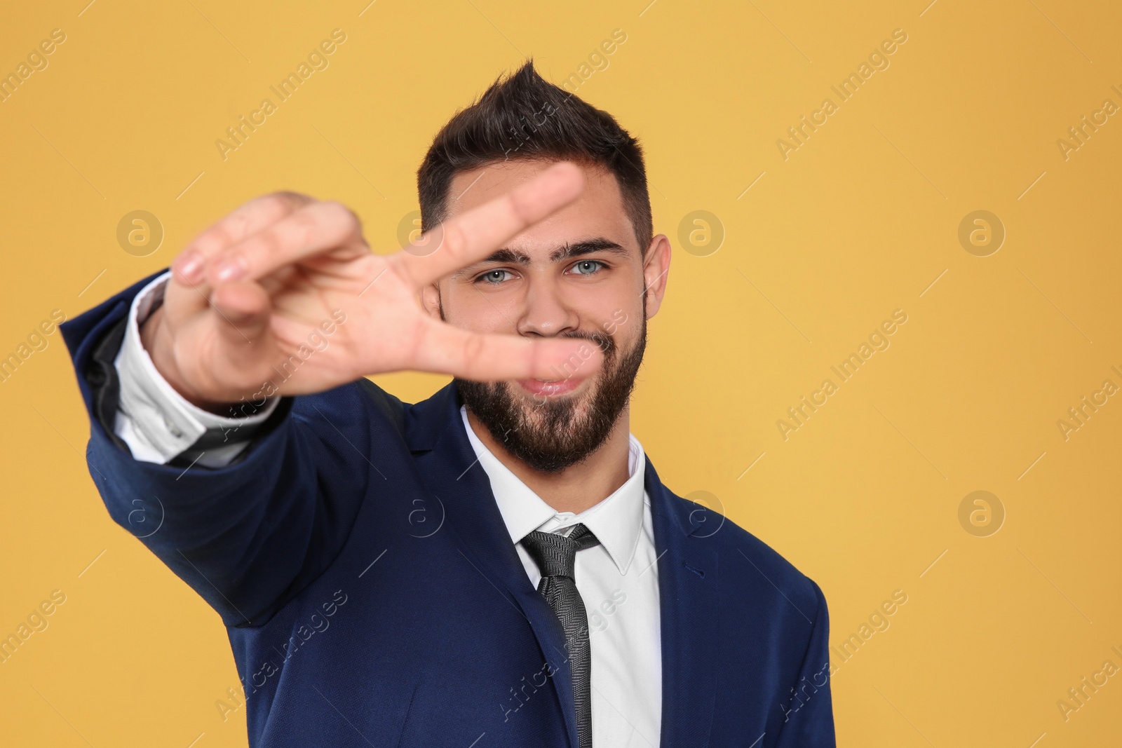 Photo of Happy young businessman showing victory gesture on color background. Space for text