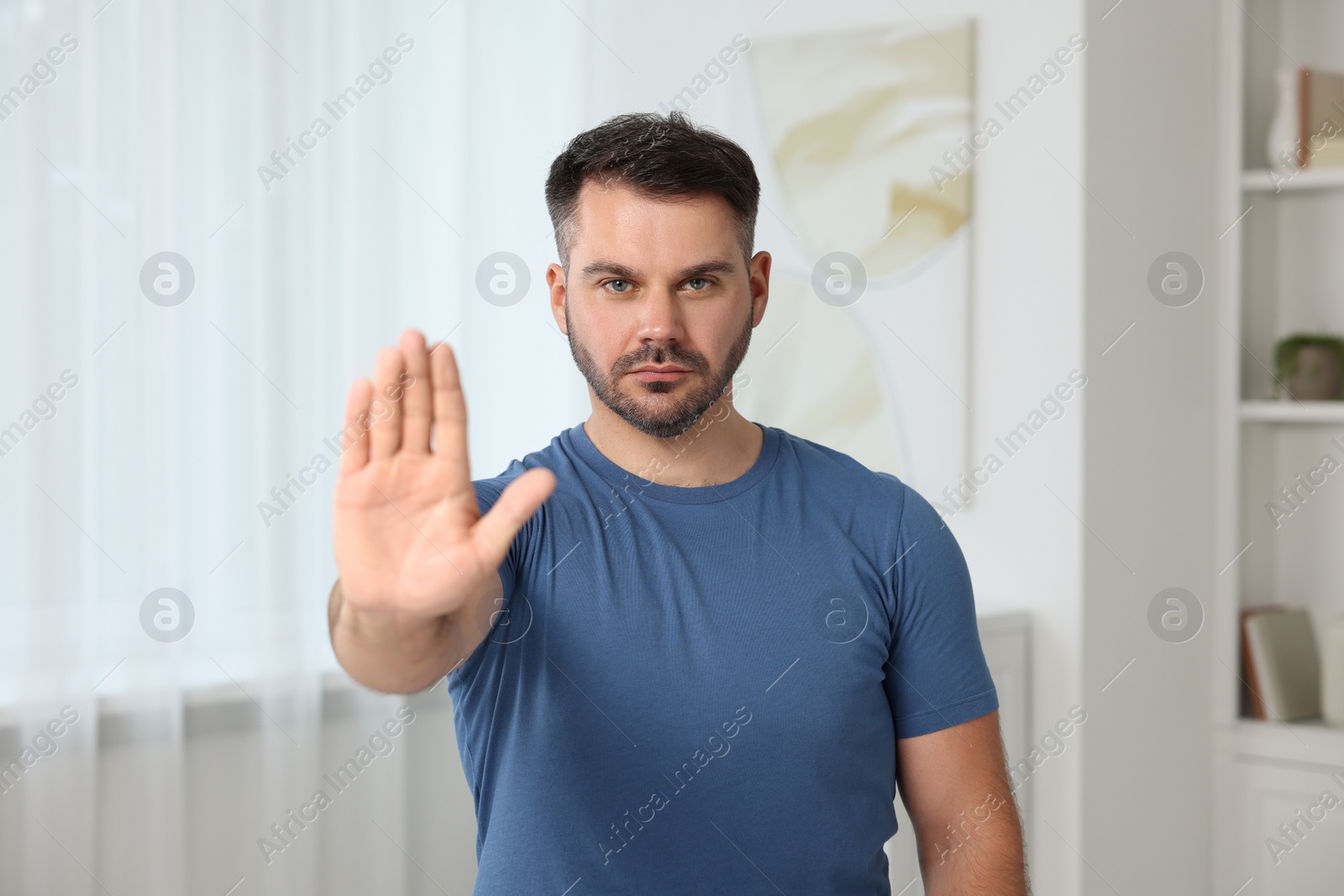 Photo of Handsome man showing stop gesture at home