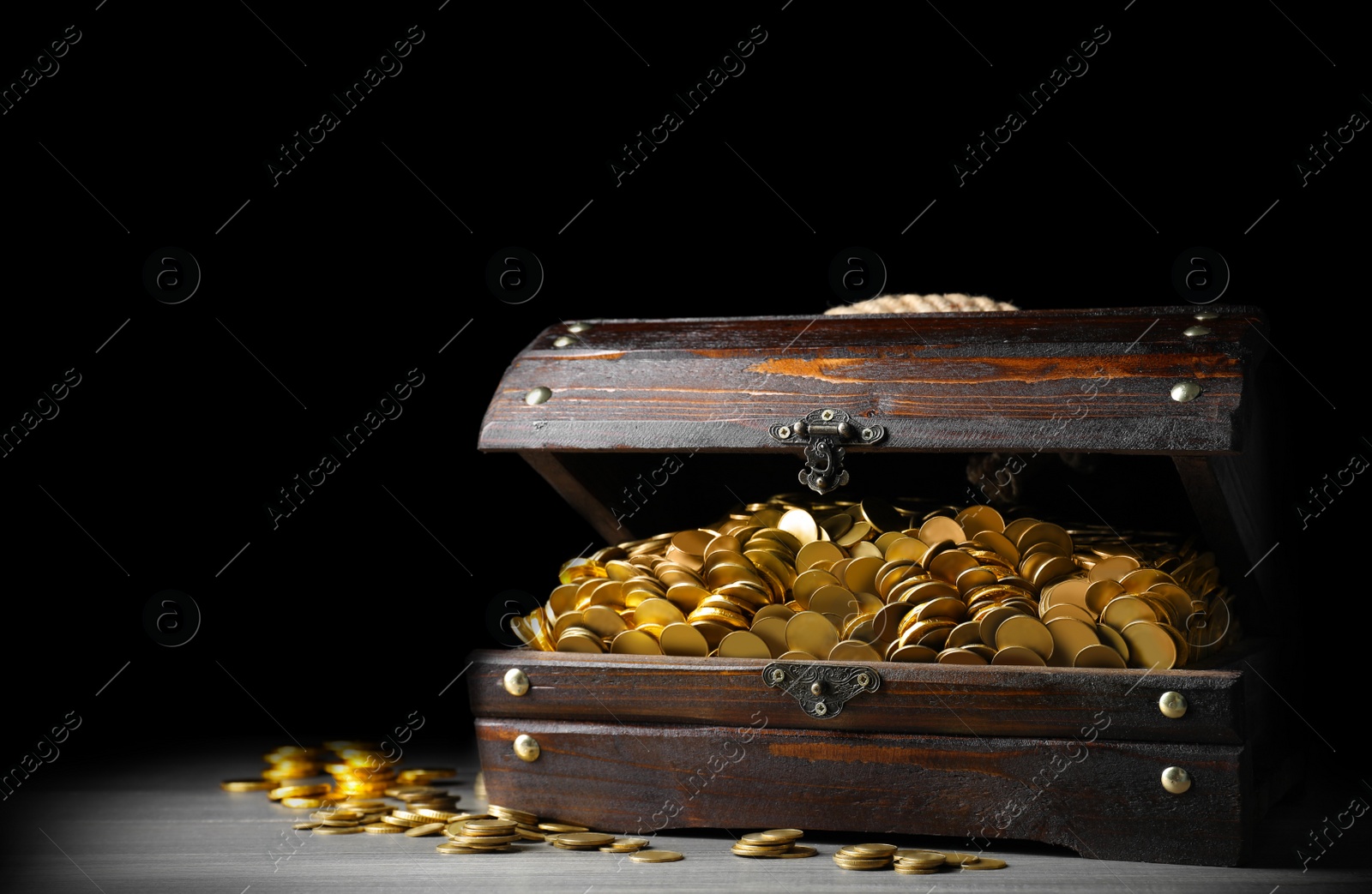 Image of Open treasure chest with gold coins on grey wooden table