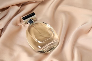 Luxury perfume in bottle on beige silk fabric