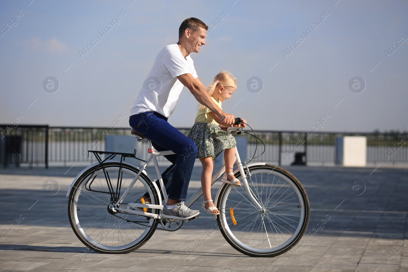 Photo of Father and daughter riding bicycle outdoors on sunny day