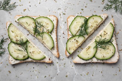 Photo of Tasty sandwiches with cream cheese, cucumber and dill on grey marble table, flat lay