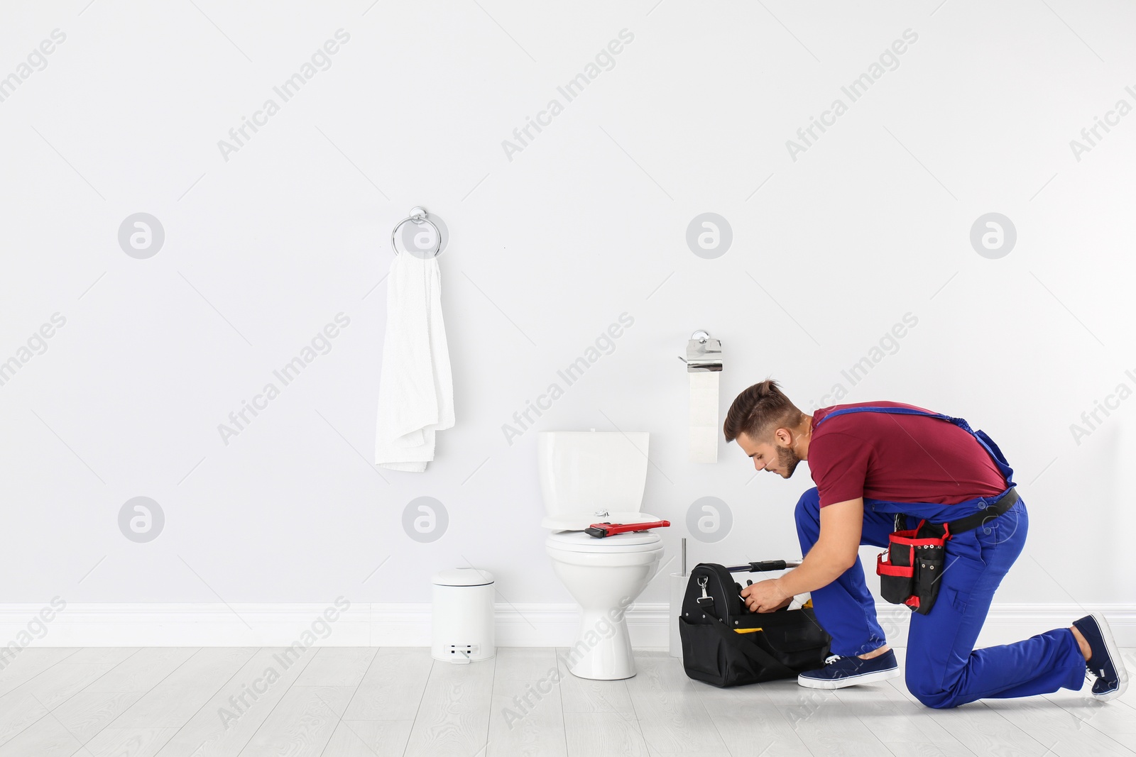 Photo of Young man with tool kit bag near toilet bowl in bathroom