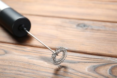 Photo of Black milk frother wand on wooden table, closeup. Space for text