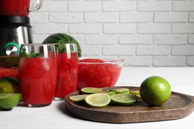 Photo of Tasty watermelon drink with lime and ingredients on white table
