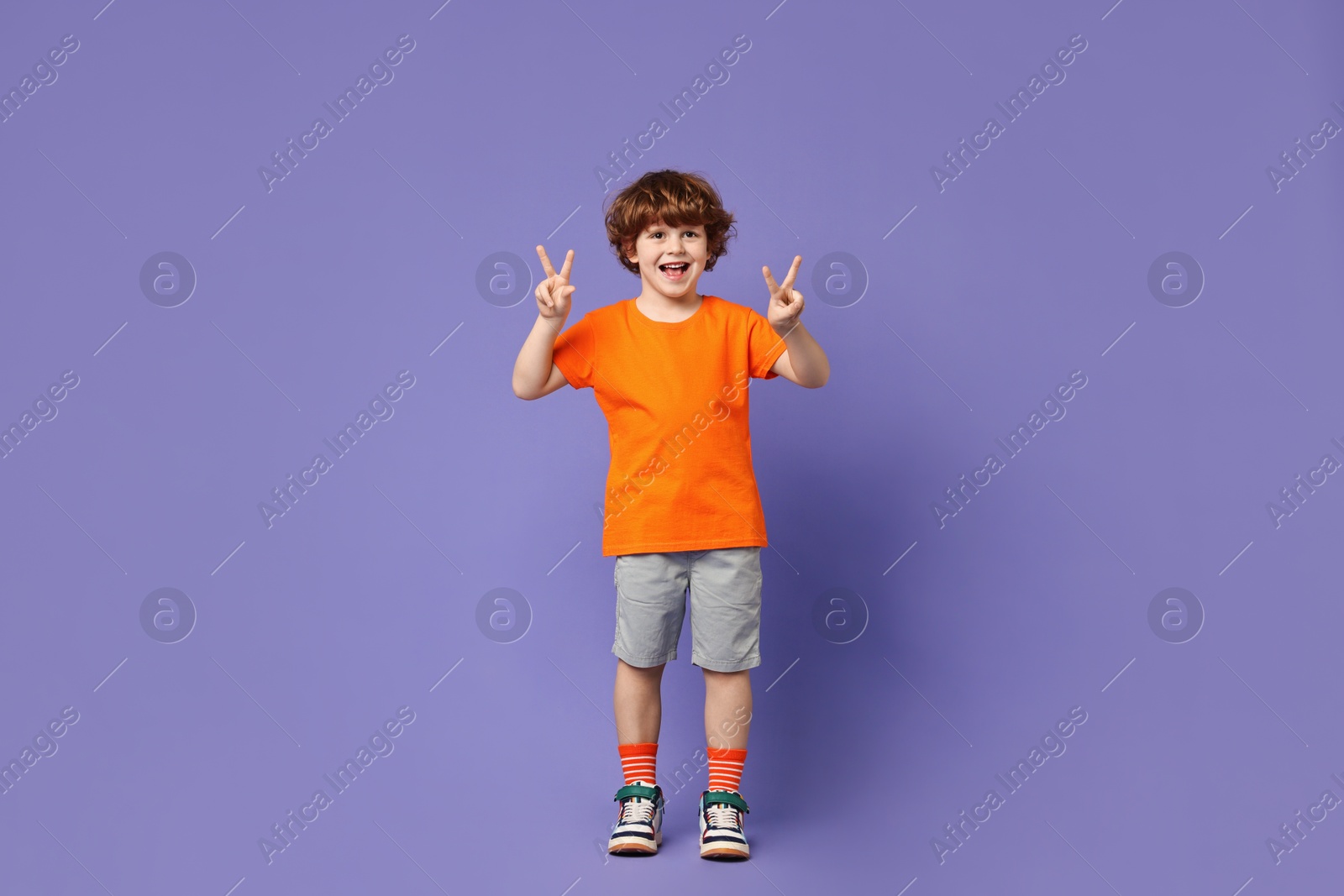 Photo of Happy little boy dancing on violet background