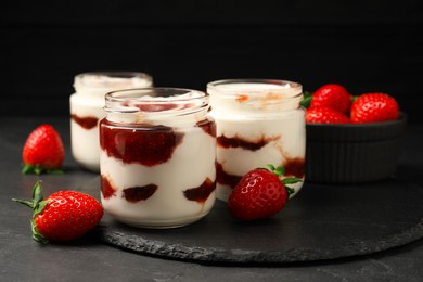 Tasty yoghurt with jam and strawberries on black table, closeup