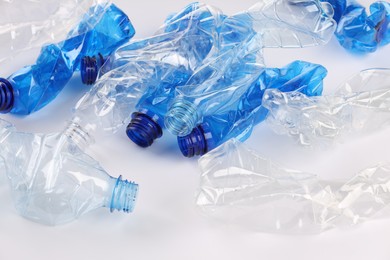 Photo of Crumpled disposable plastic bottles on white background