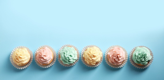 Photo of Flat lay composition with delicious cupcakes on color background, space for text