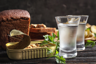 Photo of Cold Russian vodka with snacks on black wooden table, closeup