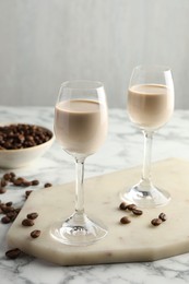 Coffee cream liqueur in glasses and beans on white marble table