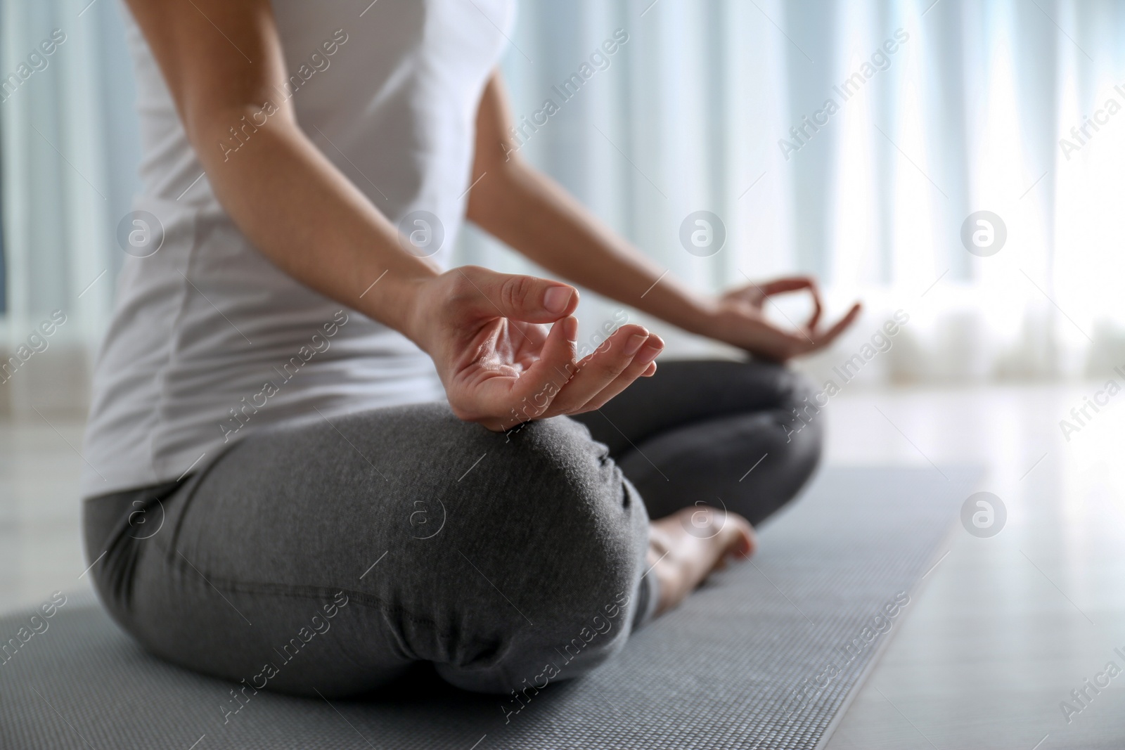 Photo of Woman practicing yoga on floor indoors, closeup. Space for text