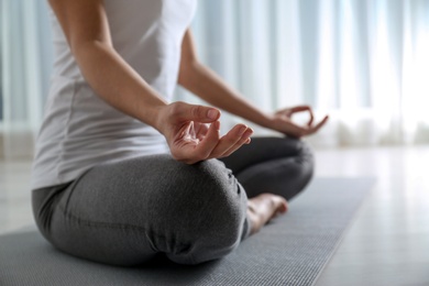 Photo of Woman practicing yoga on floor indoors, closeup. Space for text