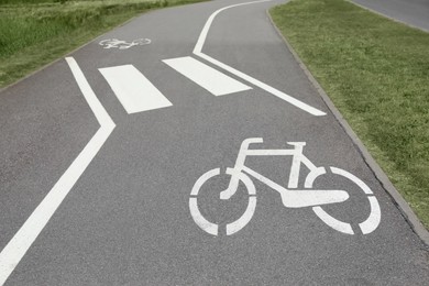 Bicycle lane with white sign painted on asphalt near sidewalk