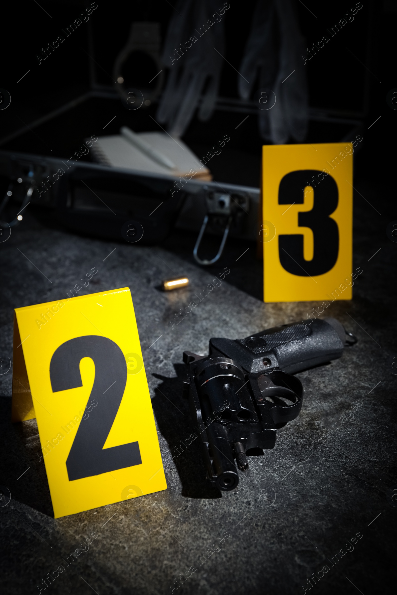 Photo of Shell casing, gun and crime scene markers on grey stone table