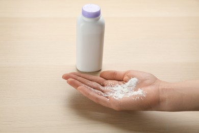 Photo of Woman with dusting powder at wooden table, closeup