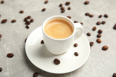 Photo of Cup of hot aromatic espresso and roasted beans on light table