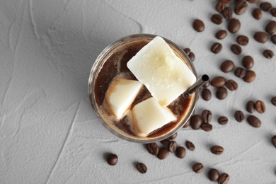 Coffee drink with milk ice cubes and beans on grey background, top view