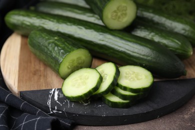 Photo of Fresh whole and cut cucumbers on table, closeup