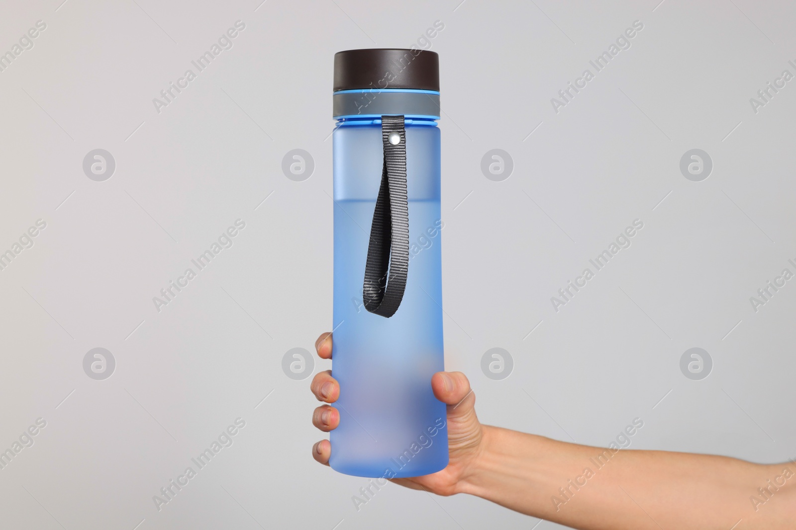 Photo of Woman holding bottle of drink on light background, closeup