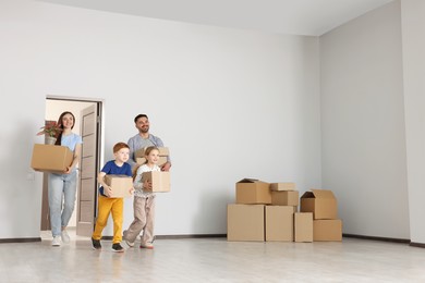 Photo of Happy family with moving boxes entering in new apartment. Settling into home