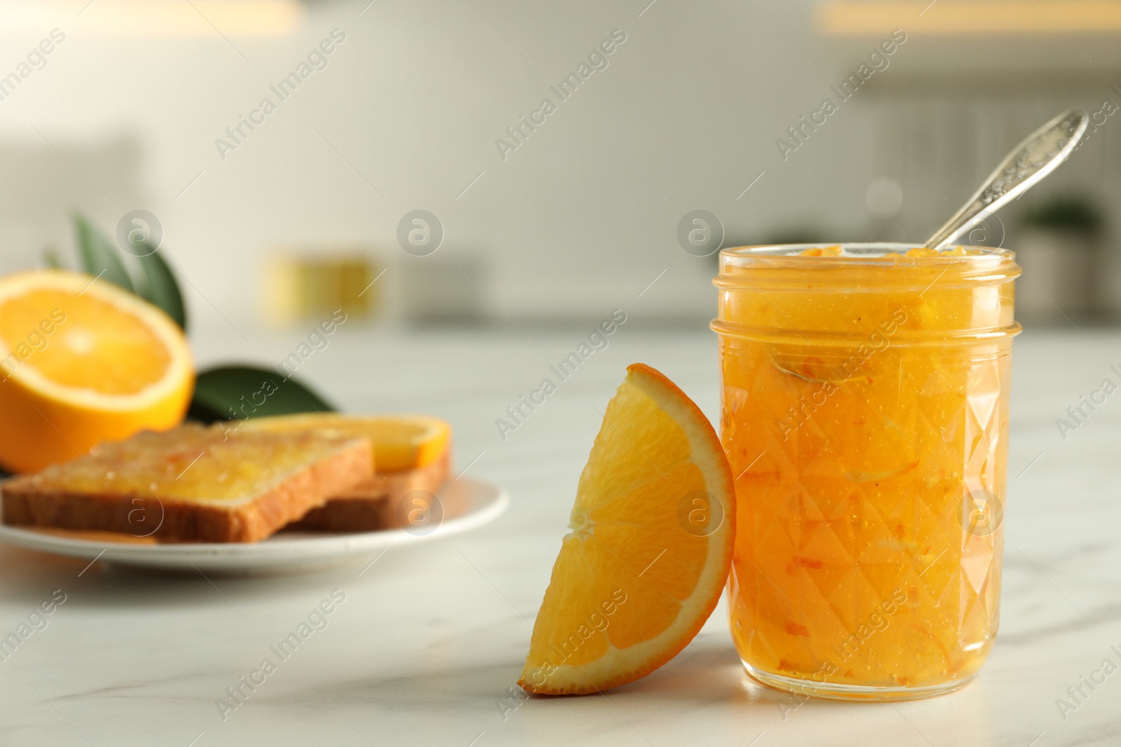 Photo of Delicious orange marmalade and citrus fruit slice on white table, closeup. Space for text