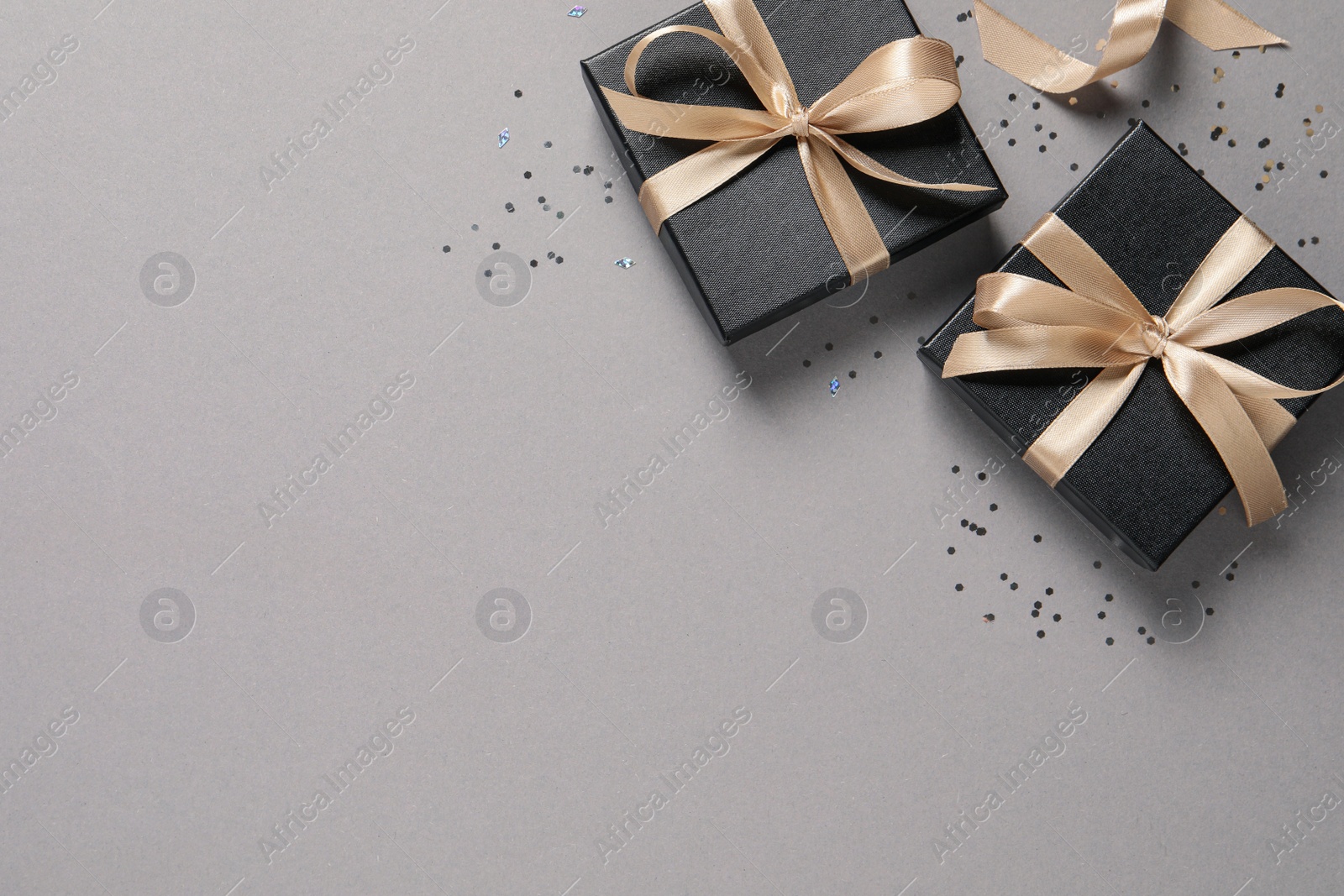 Photo of Beautiful gift boxes and confetti on grey background, flat lay. Space for text