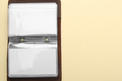 Photo of Leather business card holder with blank cards on beige background, top view. Space for text