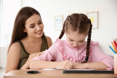 Photo of Young woman and little girl with autistic disorder drawing at home