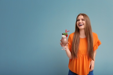 Young woman with glass of delicious milk shake on color background