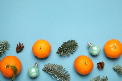 Photo of Composition with Christmas balls and tangerines on light blue background, flat lay. Space for text