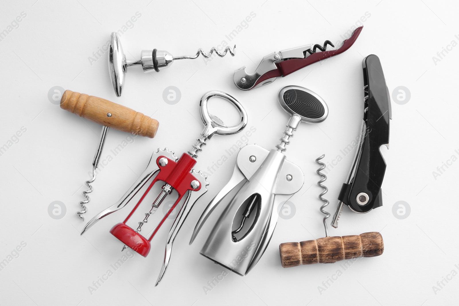 Photo of Different corkscrews on white background, flat lay