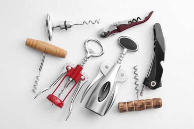 Different corkscrews on white background, flat lay