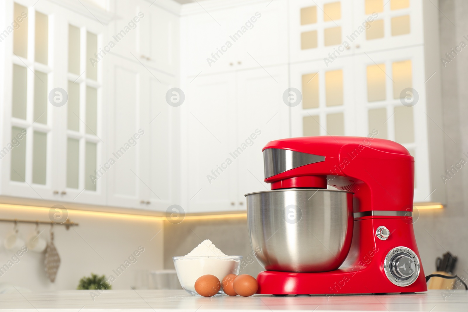 Photo of Modern red stand mixer, eggs and bowl with flour on white table in kitchen, space for text