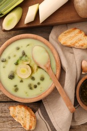 Delicious leek soup on wooden table, flat lay