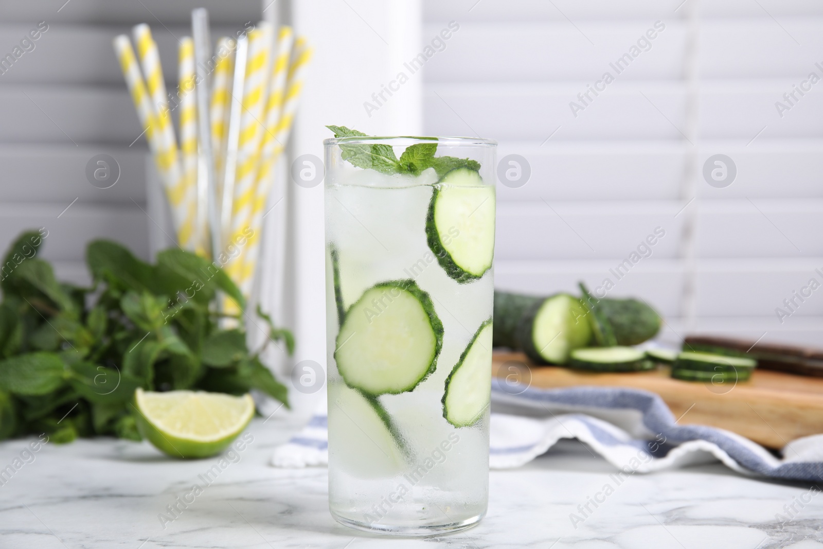 Photo of Glass of refreshing cucumber water with mint on white marble table