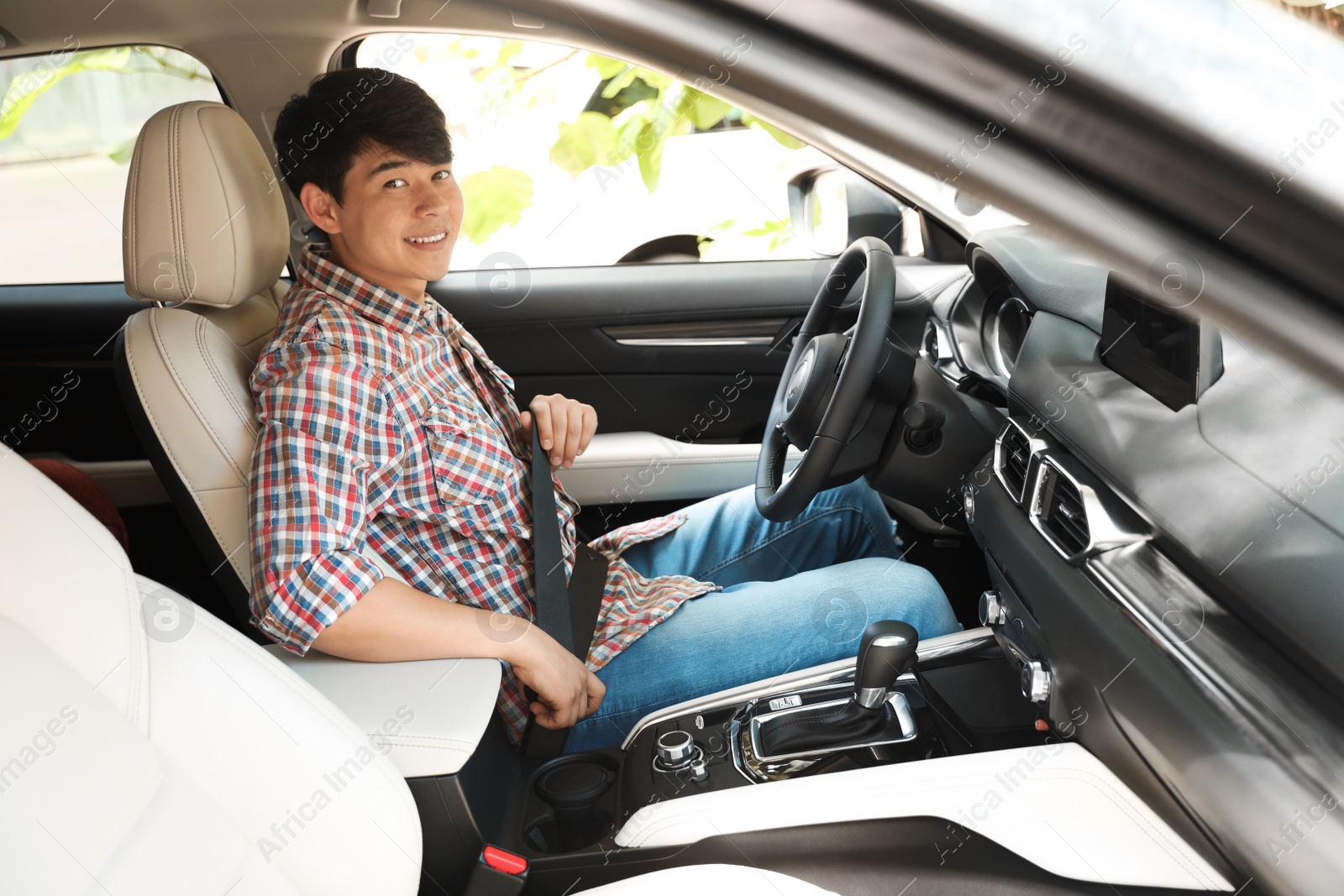 Photo of Male driver fastening safety belt in car