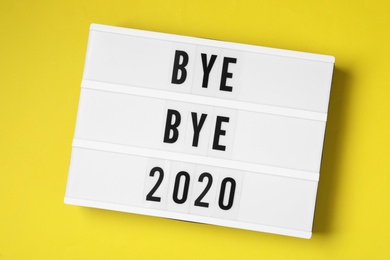 Photo of Lightbox with text Bye Bye 2020 on yellow background, top view