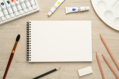 Photo of Flat lay composition with blank sketchbook on wooden table. Space for text