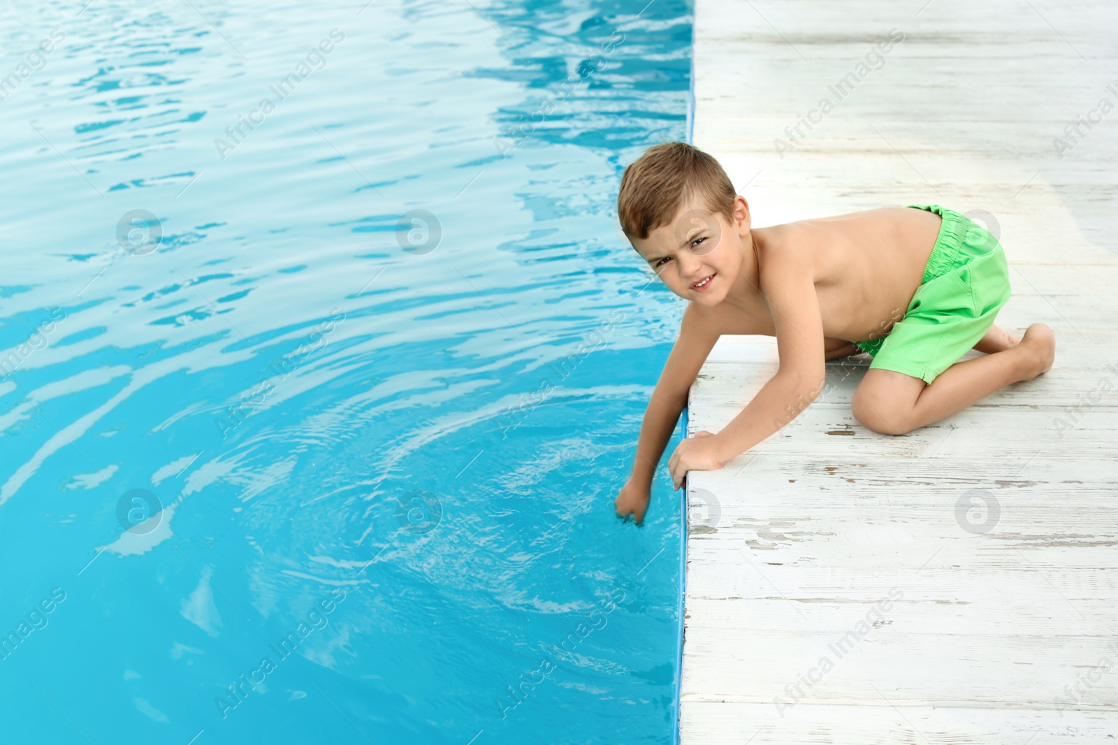 Photo of Little child near outdoor swimming pool. Dangerous situation