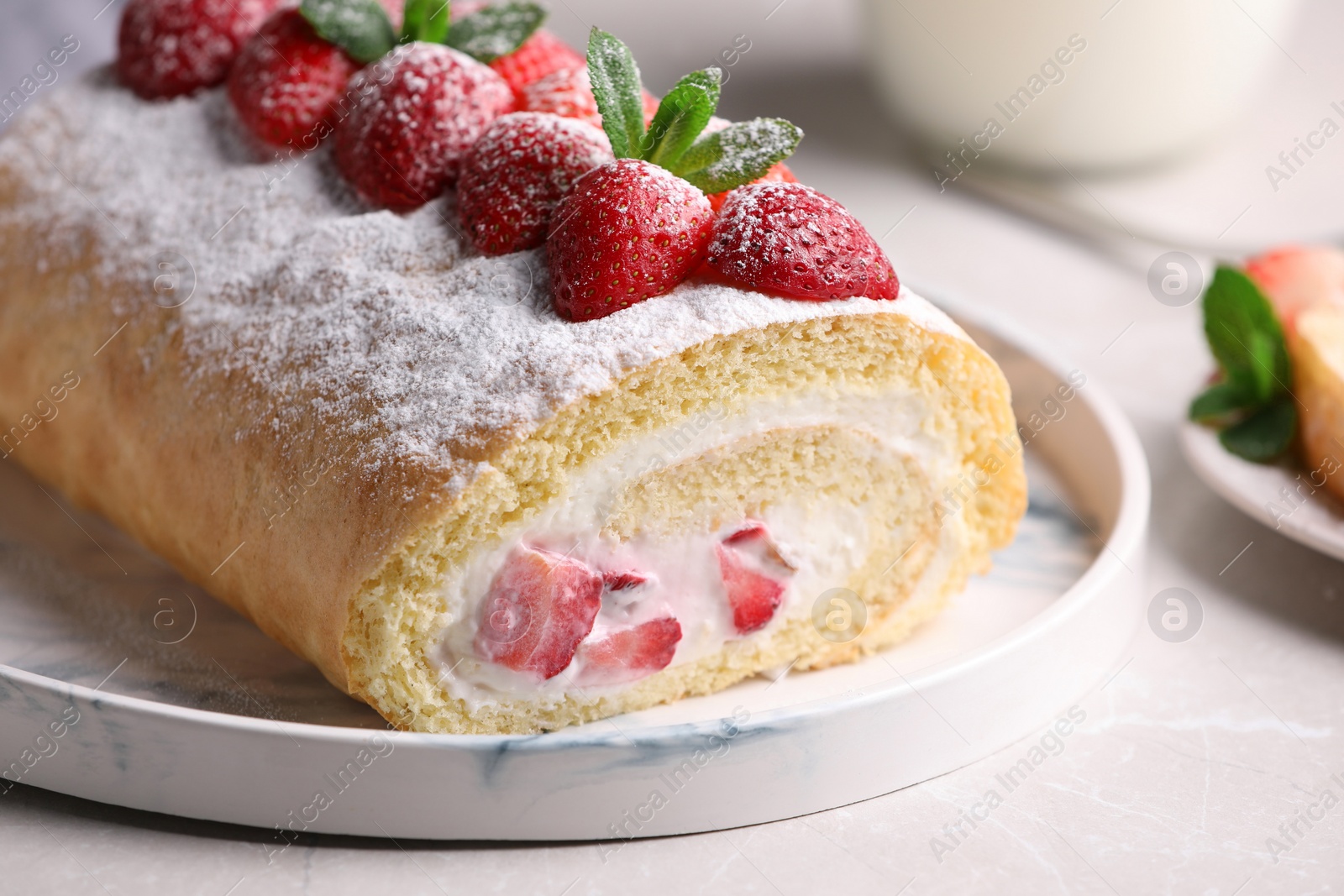 Photo of Delicious cake roll with strawberries and cream on light gray table, closeup