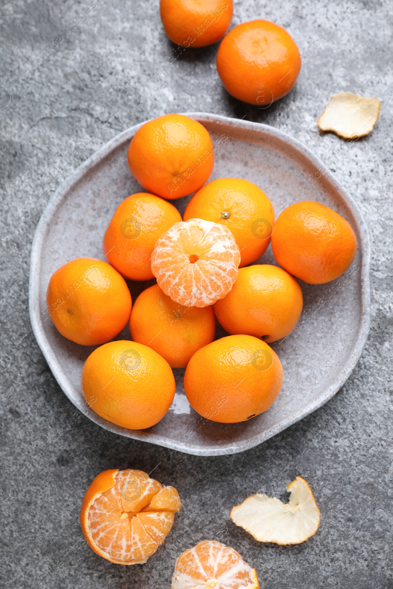 Photo of Fresh ripe tangerines and peel on grey table, flat lay