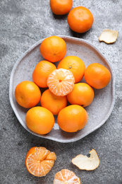 Fresh ripe tangerines and peel on grey table, flat lay