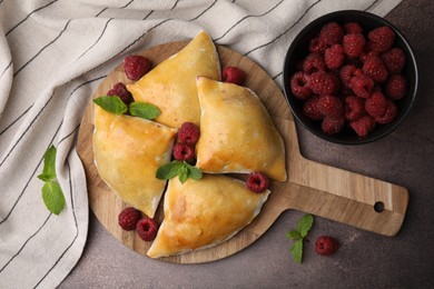 Photo of Delicious samosas with raspberries on grey table, flat lay