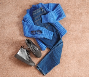 Photo of Flat lay composition with jeans, sweater and shoes on color fabric