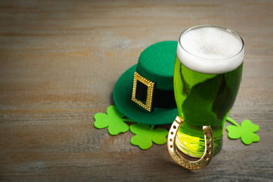 Photo of Composition with green beer and clover leaves on wooden table, space for text. St. Patrick's Day celebration