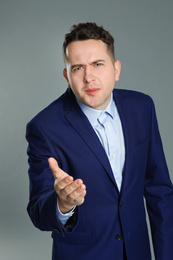 Portrait of emotional young businessman on grey background