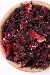 Dry hibiscus tea in bowl on white table, closeup