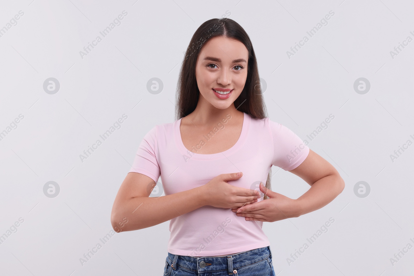 Photo of Beautiful young woman doing breast self-examination on white background
